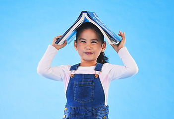 Image showing School, head and portrait of child with book for knowledge or learning isolated in a studio blue background. Clever, smart and young girl kid with notebook happy for education, story or reading