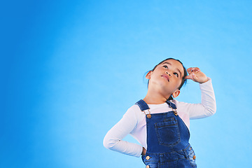 Image showing Children, thinking and a girl on a blue background mockup in studio for marketing or advertising. Banner, space and idea with a cute young child posing for a decision on kids fashion or style