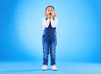 Image showing Shocked, wow and girl surprise with hands to face in studio with fear and scared from danger. Alarm, blue background and young child from Hawaii with scary, omg and emoji face of a kid in danger