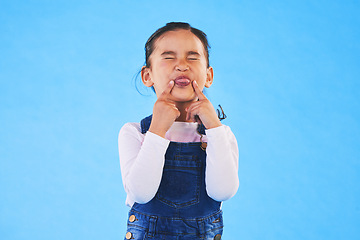 Image showing Child, funny, face and girl with silly, goofy or facial expression on blue background in studio with fashion for children. Kid, portrait and tongue out of mouth in joke, humor or emoji for comedy