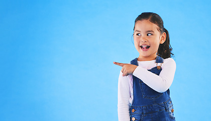 Image showing Pointing, blue background and child with mockup space for banner, advertising and promotion. Excited, happy and young girl in studio with hand gesture for discount information, announcement and news