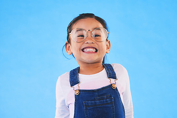 Image showing Girl kid, glasses and vision in studio with smile, medical and thinking for eye care by blue background. Female child, test spectacles and young fashion model with lens, frame and excited for health