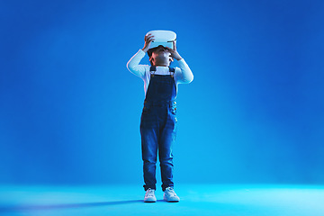 Image showing Glasses, virtual reality and metaverse with girl, online games or digital transformation on blue studio background. Kid, child and model with vr headset with technology, futuristic and live streaming