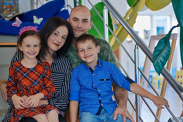 Image showing Portrait of a happy family. Photo of parents with children in a modern preschool classroom. Selective focus