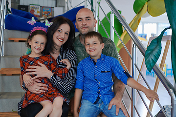 Image showing Portrait of a happy family. Photo of parents with children in a modern preschool classroom. Selective focus