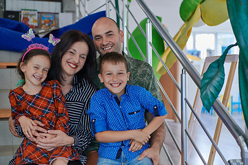 Image showing Portrait of a happy family. Photo of parents with children in a modern preschool classroom. Selective focus