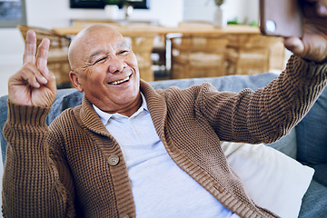 Image showing Selfie, peace sign and happy senior man on sofa smile for social media, online post and profile picture. Technology, retirement and elderly person take photo with emoji, hand gesture or relax in home