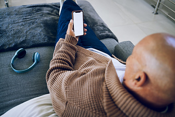 Image showing Phone screen, mockup and a man on a home sofa for internet advertising with social media or a website. Behind a person with a smartphone and blank space for network, streaming music and headphones