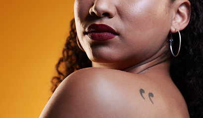 Image showing Beauty, makeup and a woman with a tattoo in studio for cosmetics, skin glow and dermatology. Closeup of a young female model on an orange background in studio with body art, confidence and comma ink