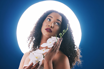 Image showing Beauty, circle light and woman with flowers for wellness, natural cosmetics and skincare in studio. Spa, neon aesthetic and person with orchid for makeup, face glamour and facial on blue background