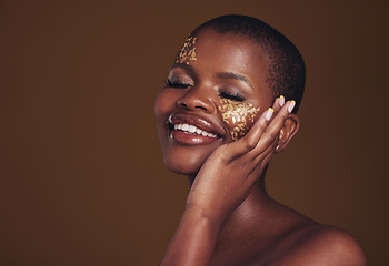 Image showing Gold, makeup and woman with a smile from luxury treatment and facial spa mask. Glitter art, creative dermatology and African female person from skincare and cosmetics in studio with brown background