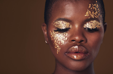 Image showing Gold, face and black woman with makeup for beauty aesthetics isolated in a studio brown background eyes closed. Creative, luxury and African person with cosmetic glamour, art or design for skincare