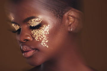Image showing Gold beauty, blur and black woman with makeup and face closeup with cosmetics in studio. Brown background, African female model and glitter with golden shine and glow from facial paint sparkle
