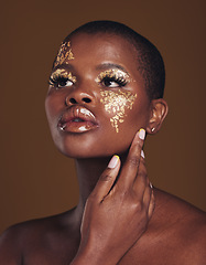 Image showing Art, aesthetic and black woman with gold makeup and brown background with glitter, paint and cosmetics. Shine, glow and African model in studio for beauty, fashion and freedom in luxury skincare.