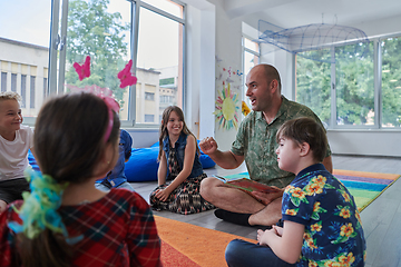 Image showing Reading time in an elementary school or kindergarten, a teacher reading a book to children in an elementary school or kindergarten. The concept of pre-school education. Selective focus