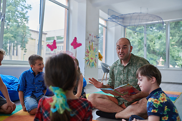 Image showing Reading time in an elementary school or kindergarten, a teacher reading a book to children in an elementary school or kindergarten. The concept of pre-school education. Selective focus