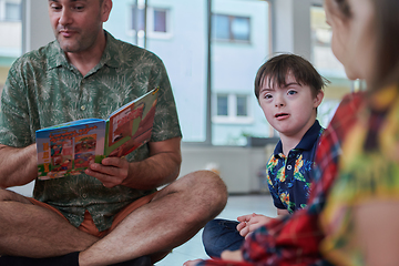 Image showing Reading time in an elementary school or kindergarten, a teacher reading a book to children in an elementary school or kindergarten. The concept of pre-school education. Selective focus