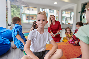 Image showing Reading time in an elementary school or kindergarten, a teacher reading a book to children in an elementary school or kindergarten. The concept of pre-school education. Selective focus