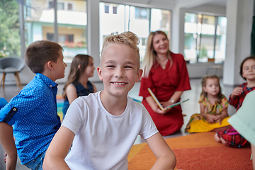 Image showing Reading time in an elementary school or kindergarten, a teacher reading a book to children in an elementary school or kindergarten. The concept of pre-school education. Selective focus