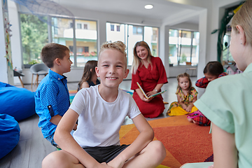 Image showing Reading time in an elementary school or kindergarten, a teacher reading a book to children in an elementary school or kindergarten. The concept of pre-school education. Selective focus