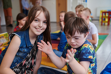 Image showing A girl and a boy with Down's syndrome in each other's arms spend time together in a preschool institution