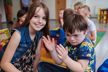 Image showing A girl and a boy with Down's syndrome in each other's arms spend time together in a preschool institution