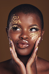 Image showing Art, fun and black woman in gold makeup on brown background, glitter paint or cosmetics. Shine, glow and silly face of African model in studio for beauty, fashion and aesthetic freedom in luxury skin