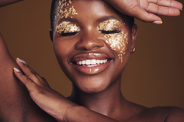 Image showing Gold, creative and art on black woman face with makeup for beauty aesthetics isolated in a studio brown background. Smile, luxury and happy person with cosmetic glamour or design for skincare