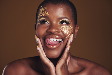 Image showing Gold, glitter face and black woman beauty with makeup and tongue out in studio with sparkle cosmetics. Brown background, funny and female model with golden paint for skin glow and creative shine