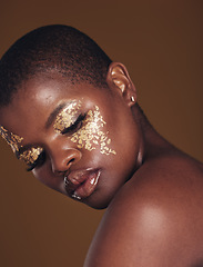 Image showing Art, glitter and black woman with gold makeup on brown background, face paint and cosmetics. Shine, glow and African model in studio for beauty, fashion and aesthetic freedom in luxury skincare.