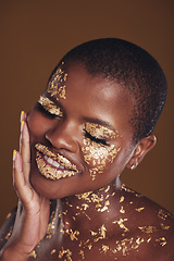 Image showing Black woman, face and gold makeup with luxury glow and skincare mask with glitter. Sparkle, smile and beauty with rich and shine of cosmetics and model in studio with facial art with brown background