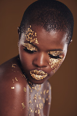 Image showing Art, facial on black woman with gold makeup and brown background, glitter paint and cosmetics. Shine, glow and African model in studio for beauty, fashion and aesthetic freedom in luxury skincare.