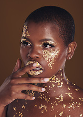 Image showing Beauty, black woman with gold paint makeup and brown background with glitter, art and cosmetics. Shine, glow and face of African model in studio for skincare, aesthetic and luxury facial with color.