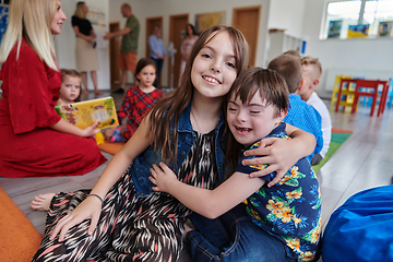 Image showing A girl and a boy with Down's syndrome in each other's arms spend time together in a preschool institution