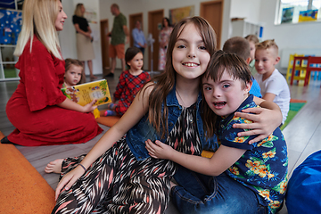 Image showing A girl and a boy with Down's syndrome in each other's arms spend time together in a preschool institution