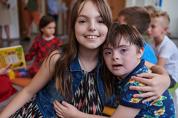 Image showing A girl and a boy with Down's syndrome in each other's arms spend time together in a preschool institution