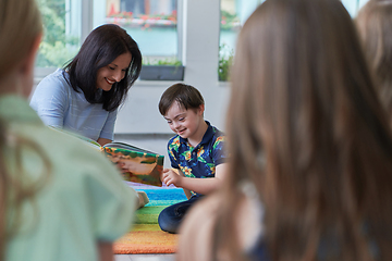 Image showing Reading time in an elementary school or kindergarten, a teacher reading a book to children in an elementary school or kindergarten. The concept of pre-school education. Selective focus