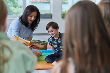 Image showing Reading time in an elementary school or kindergarten, a teacher reading a book to children in an elementary school or kindergarten. The concept of pre-school education. Selective focus