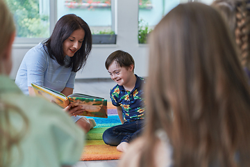 Image showing Reading time in an elementary school or kindergarten, a teacher reading a book to children in an elementary school or kindergarten. The concept of pre-school education. Selective focus