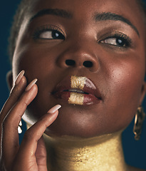 Image showing Face, beauty and black woman in gold for culture, heritage or tradition on a blue background in studio. Skincare, makeup and african style with a young model closeup for elegance or cosmetics