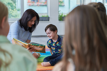 Image showing Reading time in an elementary school or kindergarten, a teacher reading a book to children in an elementary school or kindergarten. The concept of pre-school education. Selective focus