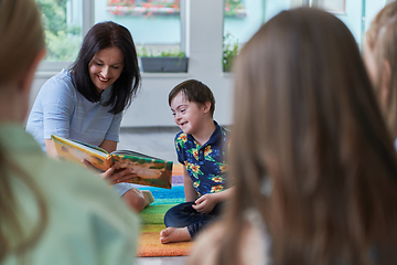 Image showing Reading time in an elementary school or kindergarten, a teacher reading a book to children in an elementary school or kindergarten. The concept of pre-school education. Selective focus