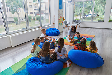 Image showing Reading time in an elementary school or kindergarten, a teacher reading a book to children in an elementary school or kindergarten. The concept of pre-school education. Selective focus