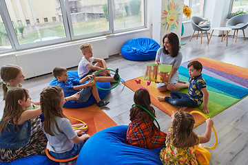 Image showing Reading time in an elementary school or kindergarten, a teacher reading a book to children in an elementary school or kindergarten. The concept of pre-school education. Selective focus