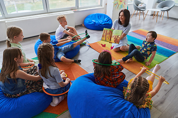 Image showing Reading time in an elementary school or kindergarten, a teacher reading a book to children in an elementary school or kindergarten. The concept of pre-school education. Selective focus