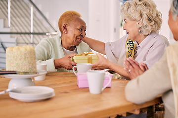 Image showing Senior friends, birthday cake and women celebration at a home with a present and gift with people. Surprise, giving and party of elderly group at a dining room table together in retirement with smile