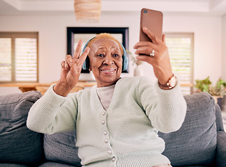 Image showing Headphones, selfie and senior woman with peace sign in home listening to music, audio and radio on sofa. Retirement, emoji and happy person in living room take photo for social media and online post