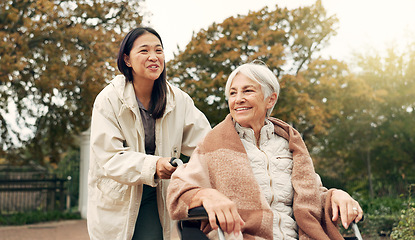 Image showing Elderly woman, wheelchair and nurse in park, nature or garden outdoor. Happy, senior person with a disability and walking with caregiver for health, wellness and physical therapy for rehabilitation