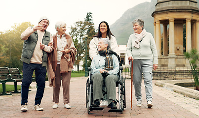 Image showing Retirement, walking and elderly friends in park for bonding, wellness and quality time together outdoor. Wheelchair, health and senior man and women with caregiver for fresh air, nature and relax
