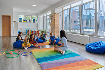 Image showing Reading time in an elementary school or kindergarten, a teacher reads a book to children in an elementary school or kindergarten. The concept of pre-school education. Selective focus